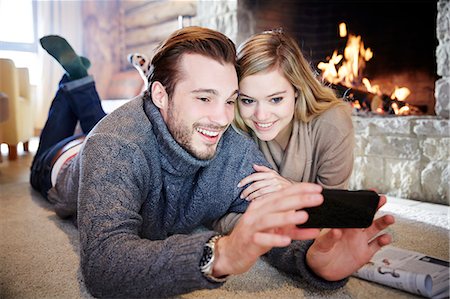 romantic couple in living room - Couple looking at cell phone together Stock Photo - Premium Royalty-Free, Code: 6113-07790607