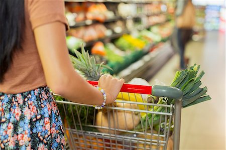 shopper - Close up of woman pushing full shopping cart in grocery store Stock Photo - Premium Royalty-Free, Code: 6113-07790948