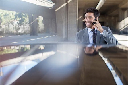 smartphone, car, smiling - Businessman talking on cell phone in parking garage Stock Photo - Premium Royalty-Free, Code: 6113-07790913