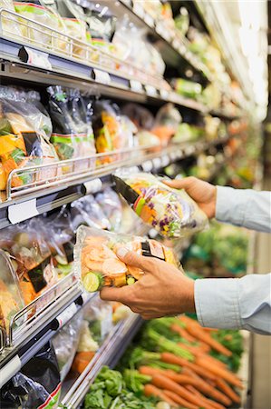 simsearch:6113-09058557,k - Close up of man comparing produce in grocery store Photographie de stock - Premium Libres de Droits, Code: 6113-07790924