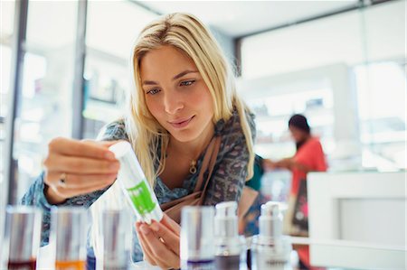 Woman examining skincare product in drugstore Photographie de stock - Premium Libres de Droits, Code: 6113-07790937