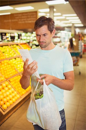 die stirn in falten legen - Confused man reading receipt in grocery store Stockbilder - Premium RF Lizenzfrei, Bildnummer: 6113-07791084