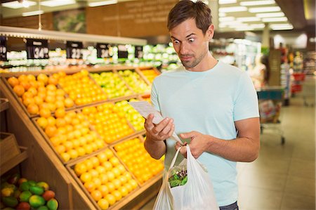 Surprised man reading receipt in grocery store Stock Photo - Premium Royalty-Free, Code: 6113-07791155