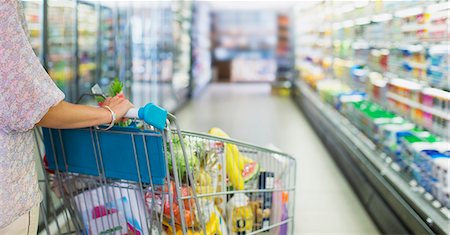 simsearch:6113-07791195,k - Woman pushing full shopping cart in grocery store Photographie de stock - Premium Libres de Droits, Code: 6113-07791167