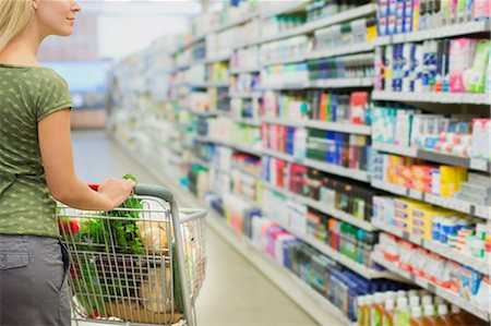 shopper at supermarket - Woman pushing full shopping cart in grocery store Stock Photo - Premium Royalty-Free, Code: 6113-07791181