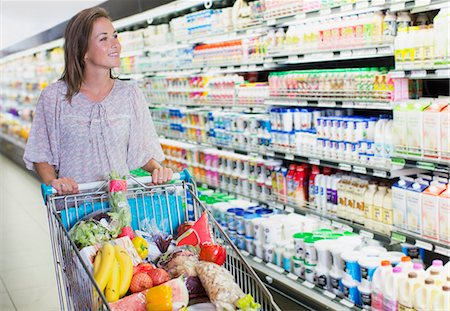 full grocery cart - Woman pushing full shopping cart in grocery store Stock Photo - Premium Royalty-Free, Code: 6113-07791105