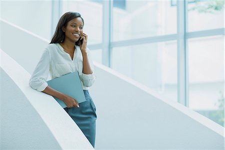 Businesswoman talking on cell phone on office building stairs Stock Photo - Premium Royalty-Free, Code: 6113-07791363