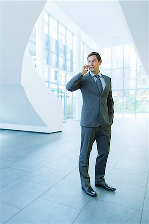 Businessman talking on cell phone in office building Stock Photo - Premium Royalty-Free, Code: 6113-07791375