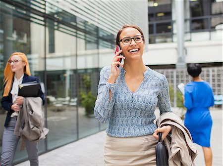 Businesswoman talking on cell phone outside of office building Stock Photo - Premium Royalty-Free, Code: 6113-07791454