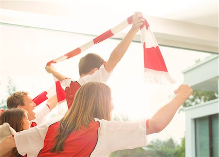 parents and children watching television - Family in sports jerseys cheering in living room Stock Photo - Premium Royalty-Free, Code: 6113-07730574