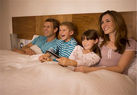 Family watching television in bed Foto de stock - Sin royalties Premium, Código: 6113-07730580