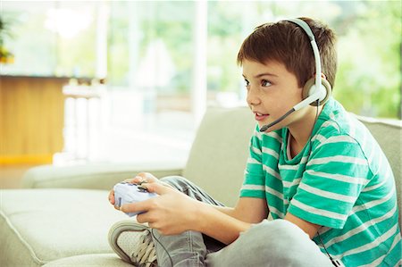 Boy playing video games on sofa Foto de stock - Sin royalties Premium, Código: 6113-07730511