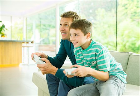 simsearch:632-02744860,k - Father and son playing video games in living room Photographie de stock - Premium Libres de Droits, Code: 6113-07730525