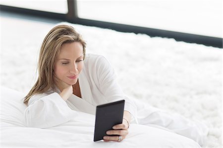 Woman in bathrobe using digital tablet in bedroom Foto de stock - Sin royalties Premium, Código: 6113-07730797