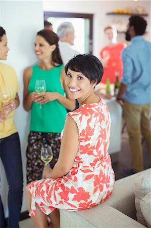 simsearch:6113-07730903,k - Woman smiling on sofa at party Photographie de stock - Premium Libres de Droits, Code: 6113-07730903