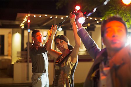 Friends stringing lights at outdoor party Photographie de stock - Premium Libres de Droits, Code: 6113-07730926