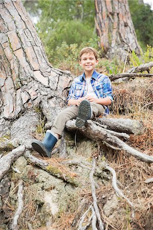 Boy sitting on tree roots in forest Photographie de stock - Premium Libres de Droits, Code: 6113-07731189