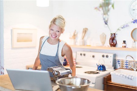Woman at laptop cooking in kitchen Stock Photo - Premium Royalty-Free, Code: 6113-07731102