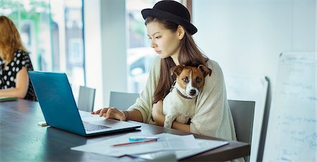 serious woman copy space office - Woman holding dog and working in office Stock Photo - Premium Royalty-Free, Code: 6113-07731373