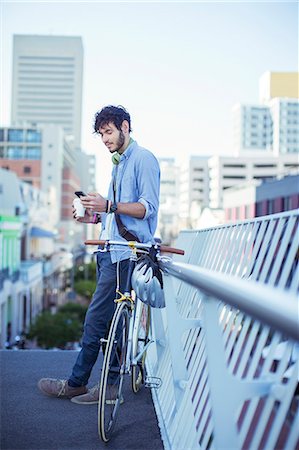 Man using cell phone on city street Stock Photo - Premium Royalty-Free, Code: 6113-07731398