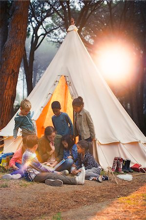 Students and teacher reading at teepee at campsite Foto de stock - Sin royalties Premium, Código: 6113-07731303