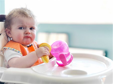 Baby girl playing with sippy cup in high chair Foto de stock - Sin royalties Premium, Código: 6113-07731329