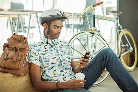 simsearch:695-05771215,k - Man in bicycle helmet using cell phone in office Stock Photo - Premium Royalty-Free, Code: 6113-07731494