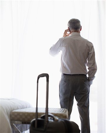 solo travel - Businessman talking on cell phone in hotel room Stock Photo - Premium Royalty-Free, Code: 6113-07731627