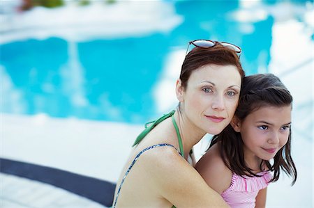 Portrait of mother and daughter sitting by swimming pool Stock Photo - Premium Royalty-Free, Code: 6113-07808113