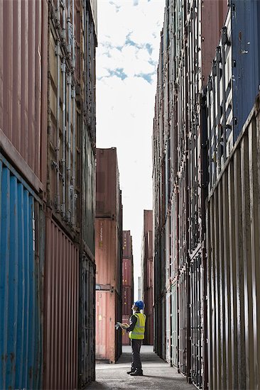 Worker standing between cargo containers Stock Photo - Premium Royalty-Free, Image code: 6113-07808387