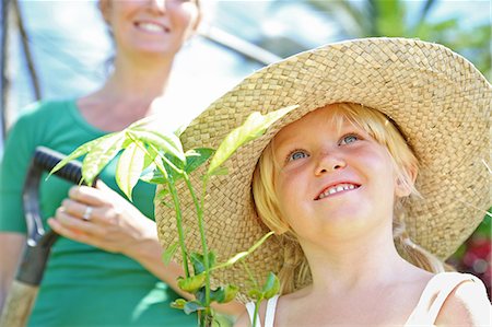 simsearch:6113-07808423,k - Girl wearing straw hat holding plant, woman with shovel in background Stock Photo - Premium Royalty-Free, Code: 6113-07808399