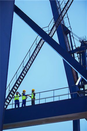 Low angle view of workers and businessman talking on cargo crane Stock Photo - Premium Royalty-Free, Code: 6113-07808327