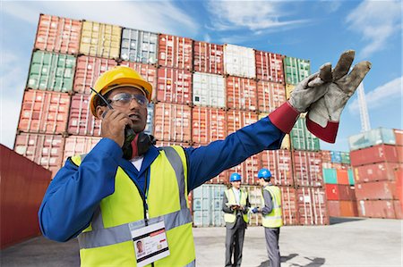 Worker using walkie-talkie near cargo containers Fotografie stock - Premium Royalty-Free, Codice: 6113-07808334