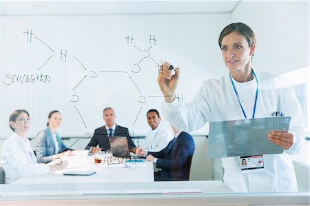 Scientist drawing chemical formula on glass for business people and colleagues Stock Photo - Premium Royalty-Free, Code: 6113-07808448