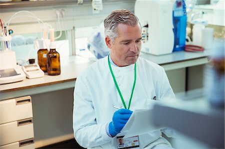 simsearch:6113-07808526,k - Scientist taking notes on experiment in laboratory Stock Photo - Premium Royalty-Free, Code: 6113-07808462