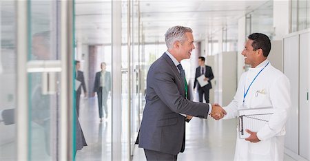 smile and greeting - Scientist and businessman shaking hands in hallway Stock Photo - Premium Royalty-Free, Code: 6113-07808481