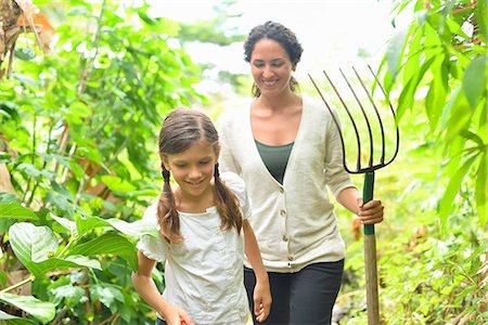 simsearch:614-06336452,k - Girl and woman with gardening fork walking through plants in greenhouse Stock Photo - Premium Royalty-Free, Code: 6113-07808402