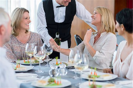 Waiter offering wine to female client at restaurant table, woman refusing Stock Photo - Premium Royalty-Free, Code: 6113-07808591