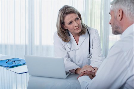 doctor comforting a patient - Female doctor sitting at desk with laptop and consoling patient Stock Photo - Premium Royalty-Free, Code: 6113-07808653