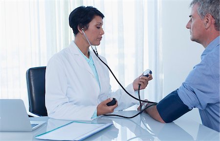 simsearch:6113-07808659,k - Female doctor taking patient's blood pressure in office Stock Photo - Premium Royalty-Free, Code: 6113-07808663