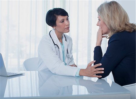 Female doctor consoling sad woman at desk in office Stock Photo - Premium Royalty-Free, Code: 6113-07808693