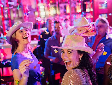 simsearch:6113-07808619,k - Confetti falling on women wearing cowboy hats laughing and dancing in nightclub Stock Photo - Premium Royalty-Free, Code: 6113-07808602