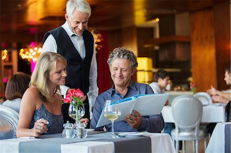 successful couple - Man ordering meal at fancy restaurant table, waiter standing behind Stock Photo - Premium Royalty-Free, Code: 6113-07808631