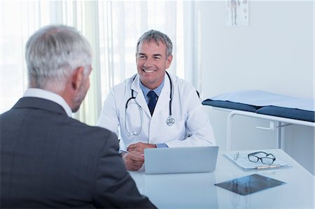 simsearch:6113-07808659,k - Smiling mature doctor and man sitting at desk in office Stock Photo - Premium Royalty-Free, Code: 6113-07808700