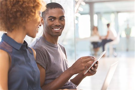 south africa technology - Man and woman using tablet in office, colleagues in background Stock Photo - Premium Royalty-Free, Code: 6113-07808851