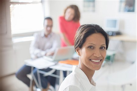 simsearch:6113-07991855,k - Portrait of smiling businesswoman in office, colleagues working in background Stock Photo - Premium Royalty-Free, Code: 6113-07808888
