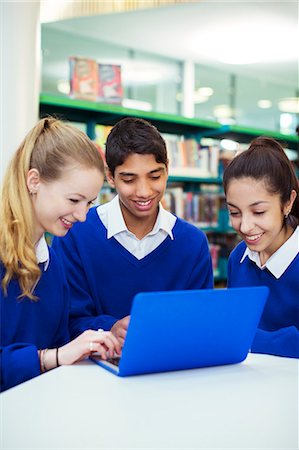 simsearch:6113-07961432,k - Three cheerful students working with laptop in library Foto de stock - Sin royalties Premium, Código: 6113-07961456