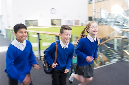 simsearch:6113-07961440,k - Happy pupils wearing school uniforms running in school corridor Foto de stock - Sin royalties Premium, Código: 6113-07961416