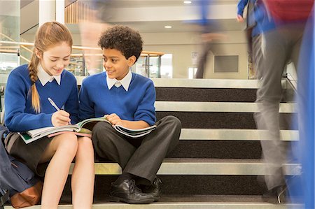simsearch:6113-07961519,k - Elementary school children wearing school uniforms sitting on steps and writing in textbooks Fotografie stock - Premium Royalty-Free, Codice: 6113-07961513