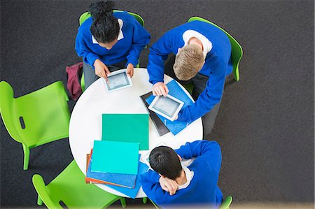 student in uniform - Overhead view of three students with digital tablets at round table Stock Photo - Premium Royalty-Free, Code: 6113-07961520
